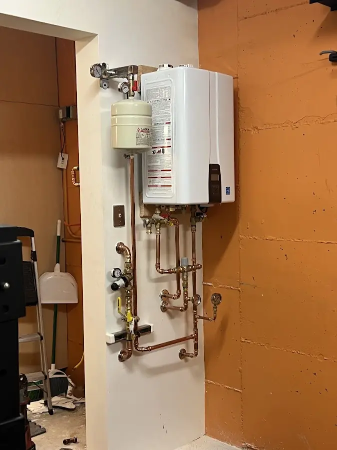 Plumbing technician inspecting water heater connections in Willard